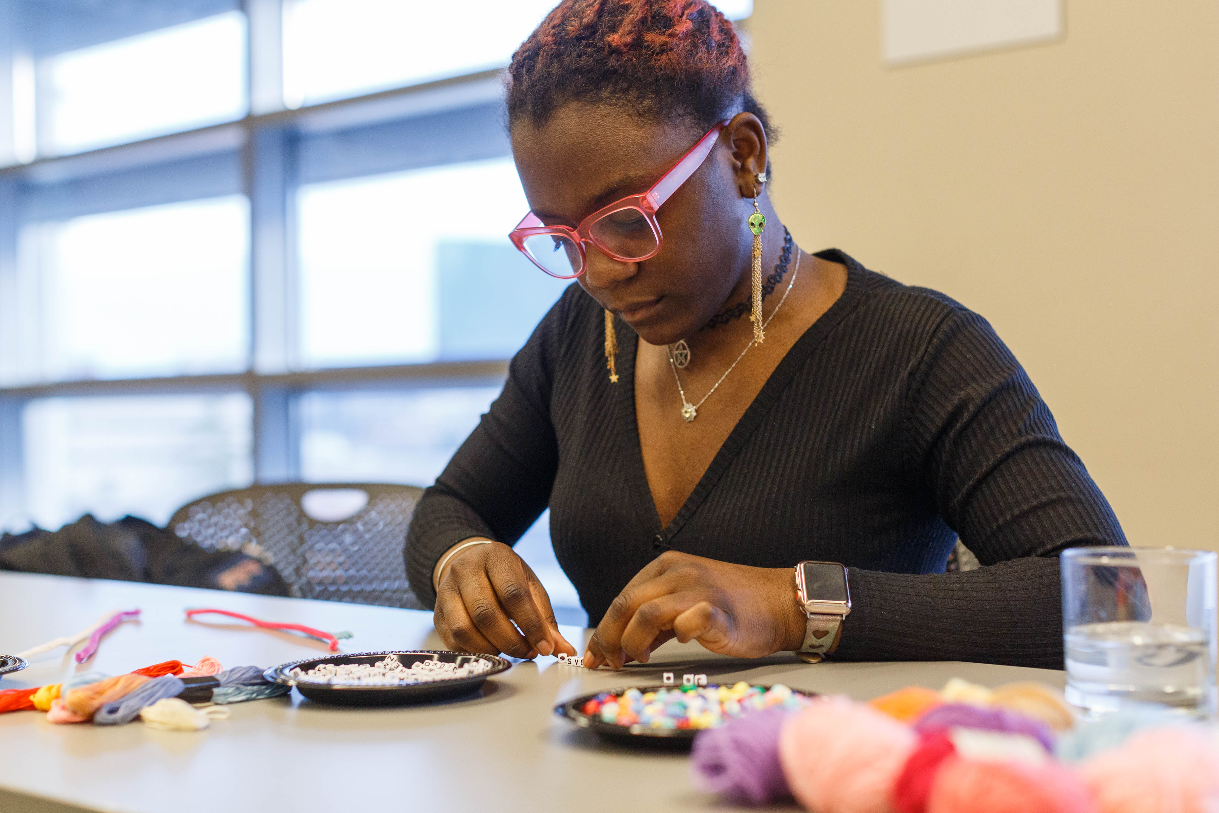 A woman is focused on making a personal wearable decoration